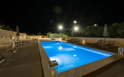 a swimming pool in a backyard at night at Queen Electra with pool and tennis court in Alikianós