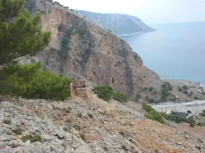 a building on a rocky hill next to the ocean at Gigilos in Agia Roumeli
