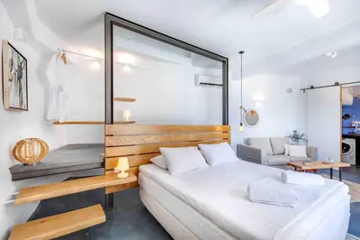 a bedroom with a white bed and a large mirror at Skiff - Transformed studio on the water's edge in Chania Town