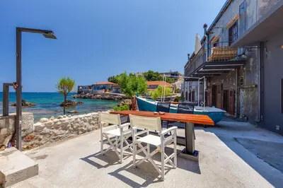 a table with two chairs and a boat on the water at Skiff - Transformed studio on the water's edge in Chania Town