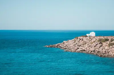 a building on a rocky island in the ocean at Fata Morgana Studios & Apartments in Frangokastello