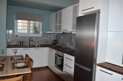 a kitchen with white cabinets and a stainless steel refrigerator at Cosy Apartments Daphne in Daratso