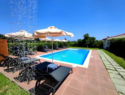 a swimming pool with umbrellas and chairs and a swimming pool at Koulouris Apartments & Studios in Kalyves