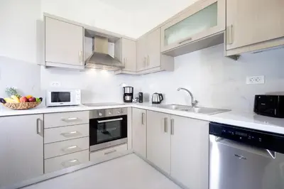 a white kitchen with white cabinets and a sink at Ariadne Apartment in Daratso