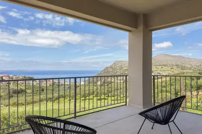 two chairs on a balcony with a view of the ocean at YaChara Villa in Kissamos