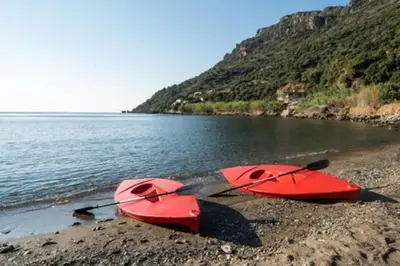 two red kayaks sitting on a beach next to the water at House just on the beach -included 2 canoe and 2 bicycles in Ravdhoúkha