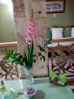 a glass vase with pink flowers on a table at Palazzo di Pietro in Chania Town