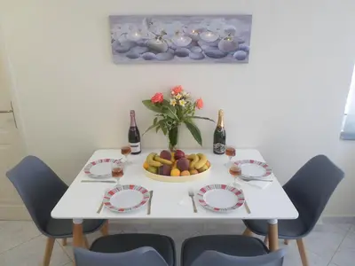 a white table with a bowl of fruit and a vase of flowers at Marias Apartment in Chania Town