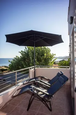 a chair and an umbrella on a balcony at 180 Degree Sea View Apartment in Palaiochóra