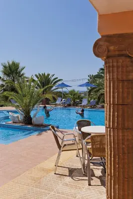a table and chairs next to a swimming pool at Tersanas Village Apartments in Tersanas