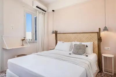a white bedroom with a large bed with white pillows at Artemide city places-Cozy Rooms in Chania Town