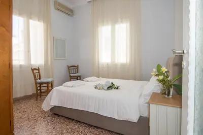 a white bedroom with a bed and two chairs at The Romantic Beach House in Chania Town