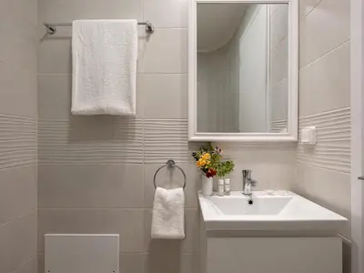 a white bathroom with a sink and a mirror at Resitour - Aphrodite Beachfront in Pírgos Psilonérou