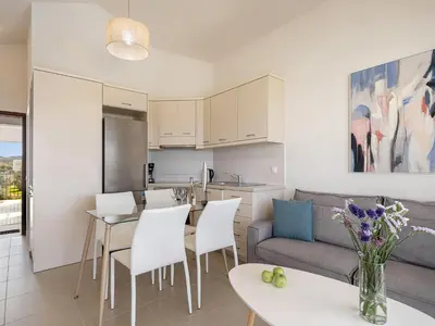 a kitchen and living room with a table and chairs at Resitour - Aphrodite Beachfront in Pírgos Psilonérou