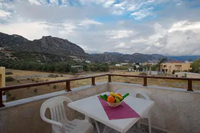 a table and chairs on a balcony with a bowl of fruit at Filoxenia Apartments 2 in Palaiochóra