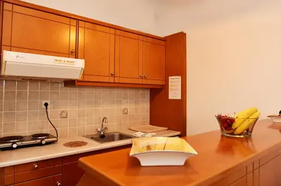 a kitchen with wooden cabinets and a counter top at Filoxenia Apartments 2 in Palaiochóra