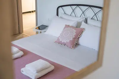 a bedroom with a white bed with a mirror at b&m villas in Metókhion Sirilíou