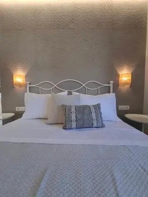 a bed with two pillows on it with two lamps at Grammeno Seaside Studios in Palaiochóra