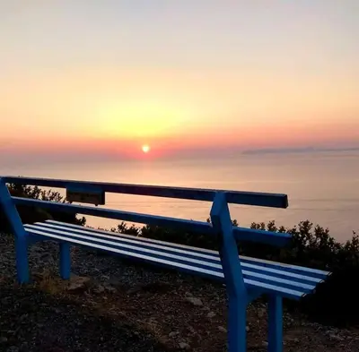 a bench with the sunset in the background at Villa Rosemari, Anatoli Apartment in Afráta