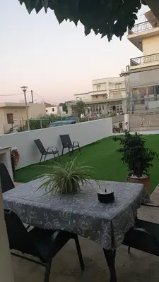 a table and chairs on a patio with a lawn at Anemelia in Chania Town