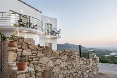 a white house with a stone wall at Magnolia Luxury Apartments in Falasarna