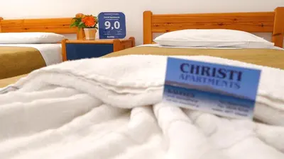 two beds with white blankets and a sign on them at Christi Apartments in Kalyves