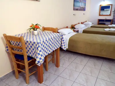 a room with two beds and a table and chairs at Christi Apartments in Kalyves