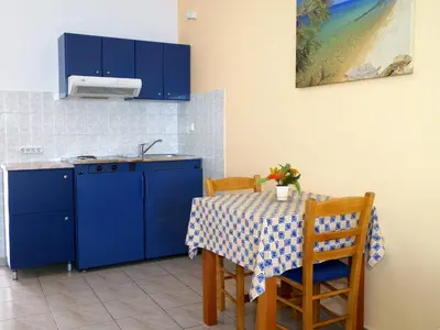 a kitchen with blue cabinets and a table with chairs at Christi Apartments in Kalyves
