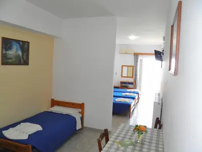 a bedroom with two beds and a table with flowers at Christi Apartments in Kalyves