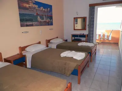 a hotel room with three beds and a view of the ocean at Christi Apartments in Kalyves