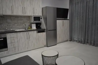 a kitchen with a stainless steel refrigerator and two tables at Paraskevi's Apartments in Kissamos