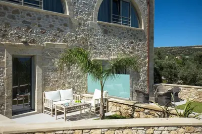 a stone house with a patio with a palm tree at Kamartsos Villa 2 in Áyios Yeóryios
