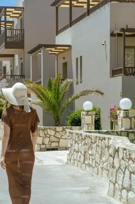 a woman walking down a sidewalk in front of a building at Erato Beach Hotel Adults Only by Smile Hotels in Plataniás