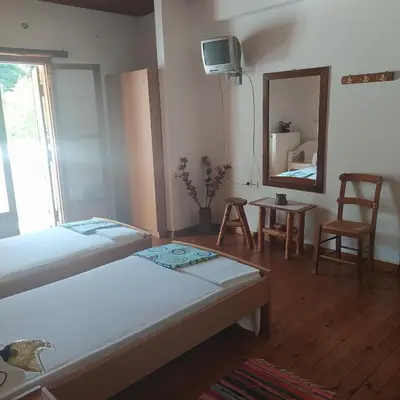 a bedroom with two beds and a mirror and a chair at Therisso Rooms in Thérison