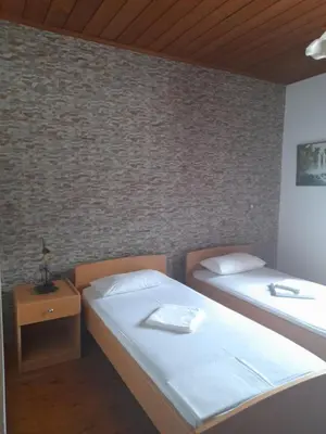 a bedroom with two beds and a brick wall at Therisso Rooms in Thérison