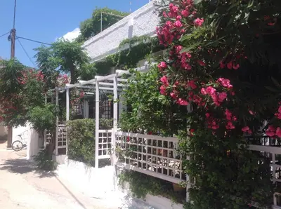 a white house with pink flowers on a fence at Kalypso Studios & Rooms in Palaiochóra