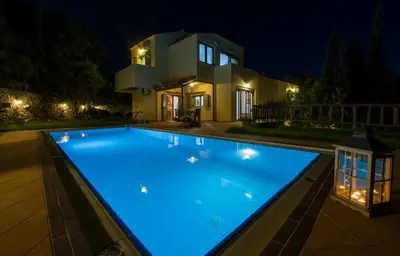 a swimming pool in front of a house at night at Malathiros Traditional Villas in Maláthiros