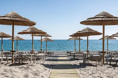 a beach with many tables and chairs and umbrellas at Euphoria Resort - All Inclusive in Kolymvari