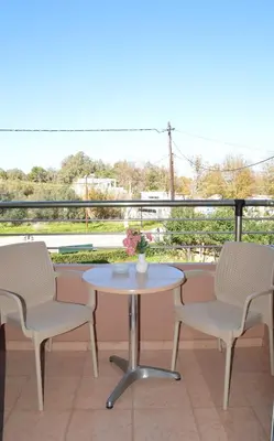 a table and chairs on a balcony with a table and flowers at Melia Studios in Kato Daratso