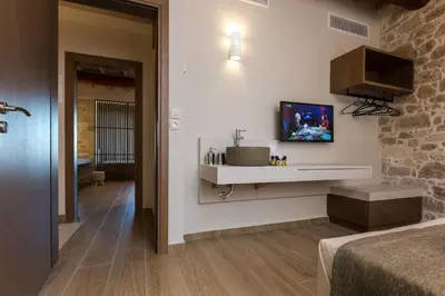 a room with a bed and a television on a wall at Kamartsos Villa 3 in Áyios Yeóryios