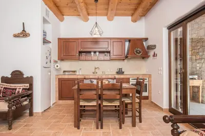 a kitchen with wooden cabinets and a table and chairs at ARADENA TRADITIONAL House 4 in Arádhaina