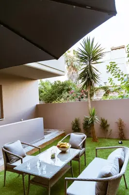 a patio with two tables and chairs under a black umbrella at Lazaretta studio in Chania Town