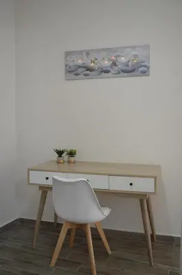 a desk with a white chair and a painting on the wall at Botonis Bright Spacious Apartment in Chania Town