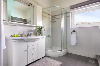 a white bathroom with a shower and a sink at Villa Elihrisos in Chorafakia