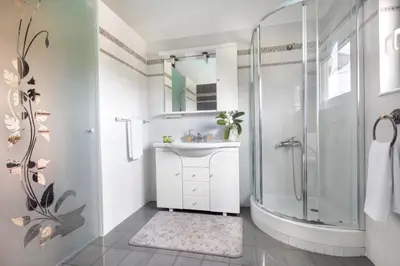 a white bathroom with a shower and a sink at Villa Elihrisos in Chorafakia