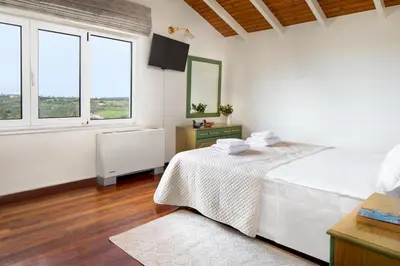 a white bedroom with a bed and two windows at Villa Elihrisos in Chorafakia