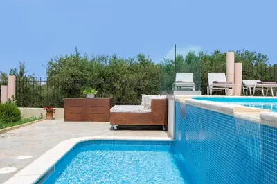 a swimming pool with a bench next to a swimming pool at Villa Elihrisos in Chorafakia