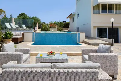 a patio with wicker furniture and a swimming pool at Villa Elihrisos in Chorafakia