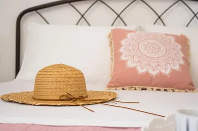 a straw hat sitting on a bed with pillows at B&M HOUSE,SIRILI,PLATANIAS in Metókhion Sirilíou