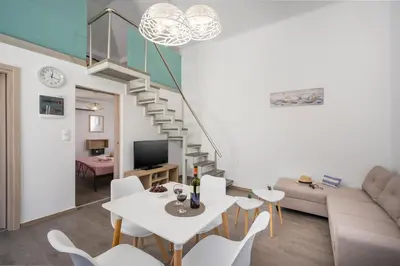 a living room with a white table and a staircase at B&M HOUSE,SIRILI,PLATANIAS in Metókhion Sirilíou